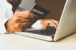 in an article about online bookmakers, someone holding a credit card in front of a computer